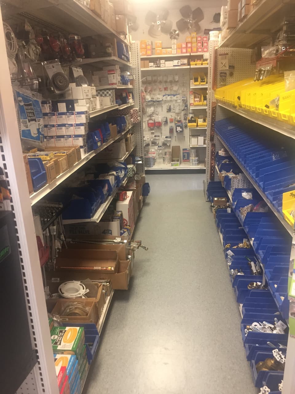 Plumbing aisle with bins of valves, drain parts and fittings at Smith Supply in Stephenville, TX