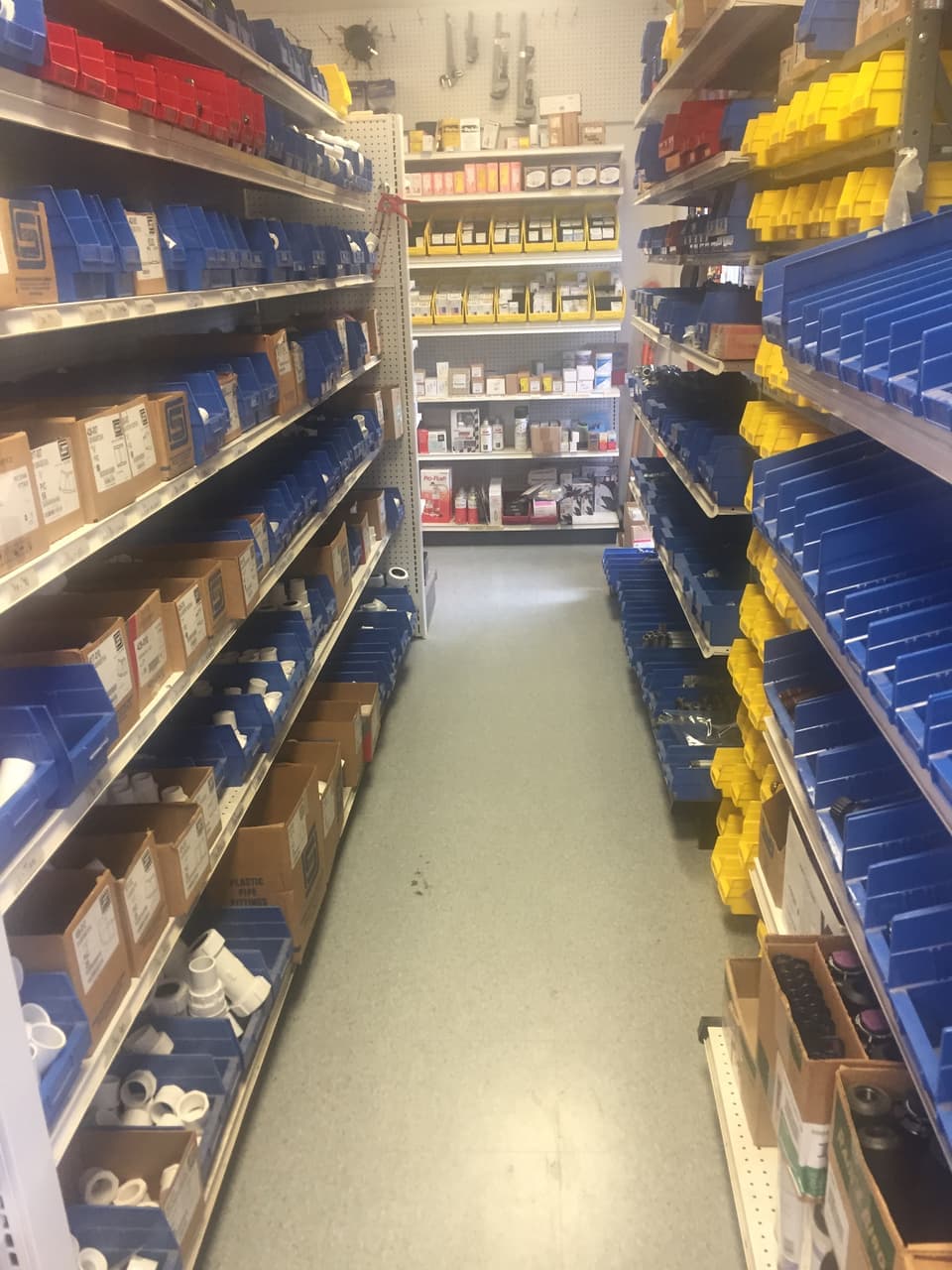 Aisle of bins and boxes of PVC pipe fittings at Smith Supply in Stephenville, TX
