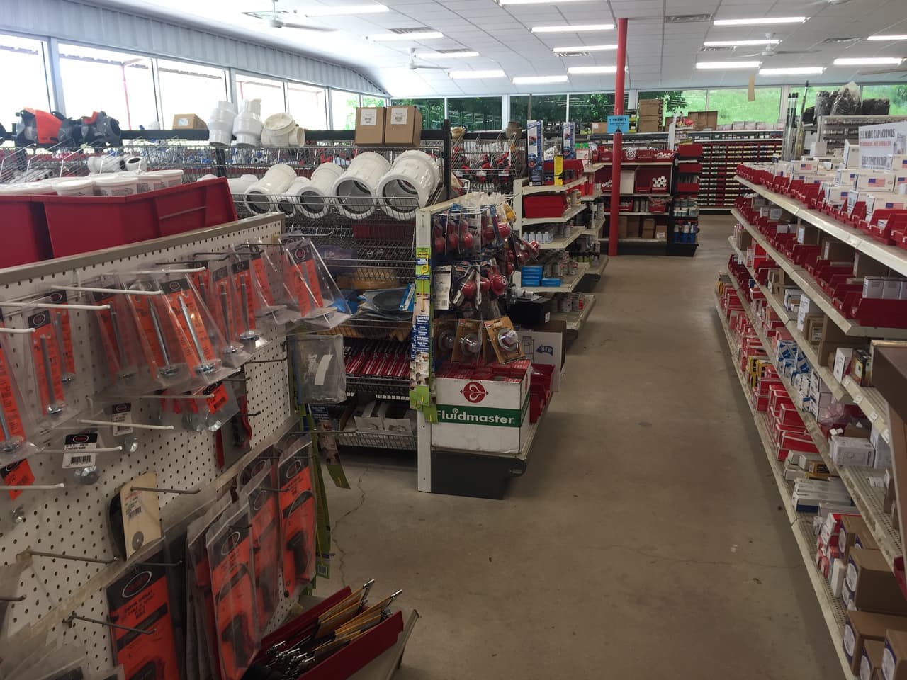 Wide aisle of plumbing and electrical supplies with red bins and PVC fittings at Smith Supply in Stephenville, TX